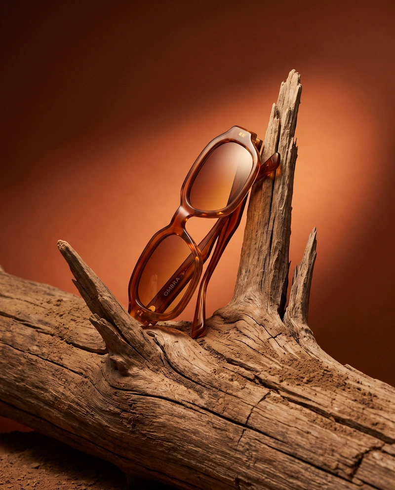 AI-generated: Vertical 4:5 editorial product photograph of designer sunglasses for the fictional eyewear brand "OMBRA". Chunky retro acetate sunglasses in